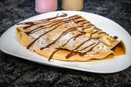 Photo for Close-Up of Pancake Drizzled with Chocolate Sauce.  Ideal for breakfast, brunch, or dessert-themed projects, this high-resolution image captures the tempting details and culinary artistry - Royalty Free Image