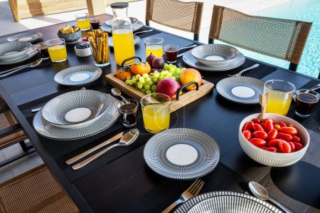 Foto de Close-Up Meal Concept: Conjunto de mesa para cenar con frutas, tomates cherry, palitos secos y jugo de naranja.Perfecto para usar en blogs de alimentos, publicaciones de estilo de vida y materiales promocionales - Imagen libre de derechos