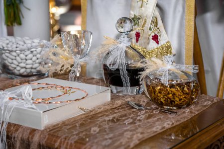Photo for Greek wedding ceremony set in a church: Stefana wedding crowns, carafe with red sweet wine, common cup, honey with nuts, and koufeta sugar coated almonds. Selective focus - Royalty Free Image
