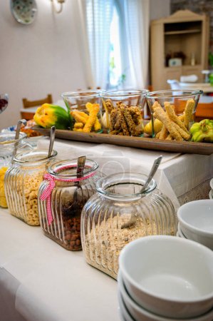 Foto de Vista de un buffet de desayuno del hotel con una atractiva selección de varios cereales y copos. La gama vibrante muestra un surtido tentador, desde avena sana hasta copos de maíz crujientes - Imagen libre de derechos