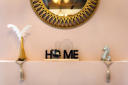 Acogedor detalle decorativo de la casa con la palabra "hogar" deletreado en letras adornadas con un globo terráqueo y pequeñas figuras decorativas colocadas a cada lado, añadiendo calidez y encanto personal 