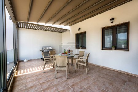 Photo for Heraklion,Crete,Greece-06.01.2024: delightful covered terrace in front of house, featuring beautifully set table with chairs and BBQ, creating inviting outdoor area for al fresco gatherings, relaxation. - Royalty Free Image