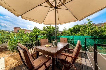 Inviting outdoor terrace adorned with wooden garden furniture, including a table sheltered by an umbrella, amidst abundant greenery, perfect for enjoying summer days. Illustration for articles or blog