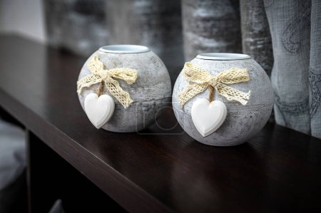 Photo for Design Element: Close-Up of Two Small Light-Colored Round Candle Holders Adorned with White Heart Decor. Perfect for enhancing interior decor, adding warmth, and infusing a sense of love and coziness - Royalty Free Image