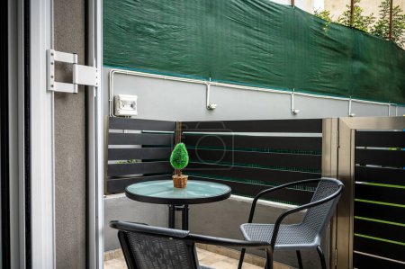 Ruhige Hinterhof-Balkon-Rückzug: Ruheecke mit Tisch und Stühlen. Ideal, um das Wesen der Freizeit im Freien zu veranschaulichen und die Schönheit von Wohnräumen zu fördern.
