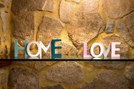 Primer plano del amor y las palabras del hogar contra la pared de piedra - Decoración interior. Perfecto para acentuar paredes en salas de estar, dormitorios o entradas. Ideal para añadir un toque de personalidad y estilo.
