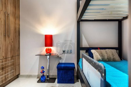 Kreative Kinderschlafzimmer-Einrichtung mit einem Etagenbett gepaart mit einem stilvollen Nachttisch, akzentuiert durch eine kräftige rote Lampe für zusätzlichen Charme und Funktionalität. Perfekt für die Innenarchitektur Inspiration