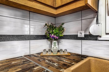 Eleganz in der Küche: Detailaufnahme der Ecke mit frischen Blumen in Vase und Karaffe mit zierlichen Gläsern