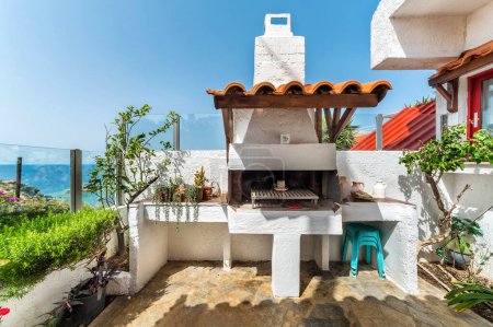 outdoor area featuring traditional Greek BBQ corner, beautifully adorned in classic white colors. BBQ area is designed with whitewashed stone and elegant architectural details. Greek outdoor living