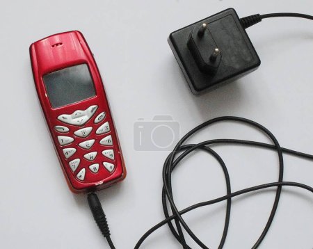 Old cell phone with charger on white background