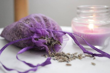 Gehackter Lavendel in einem lila Beutel und einer aromatischen Kerze