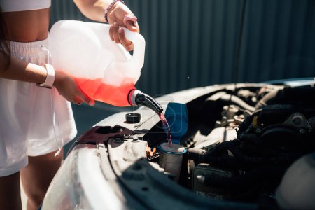 Téléchargez les photos : Femme versant le liquide de lavage d'écran de voiture d'antigel dans la voiture - en image libre de droit
