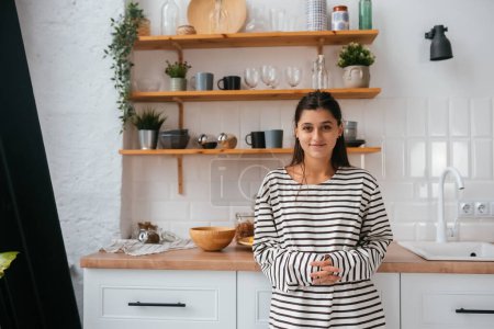 Téléchargez les photos : Femme debout près du bureau dans la cuisine - en image libre de droit