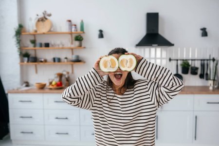 Photo for Woman hold cut fruit at eye level instead of glasses in the kitchen - Royalty Free Image
