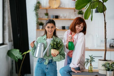 Foto de Mujeres jóvenes con una regadera y una planta de interior en una olla - Imagen libre de derechos