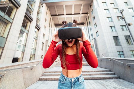 Téléchargez les photos : A woman in a virtual reality helmet walks down the street - en image libre de droit