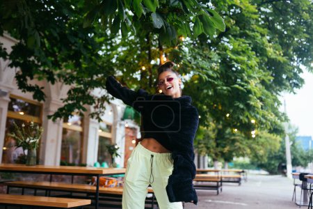 Foto de Glamorous white girl fooling around in outdoor cafe. Gorgeous brunette female model in summer day. - Imagen libre de derechos