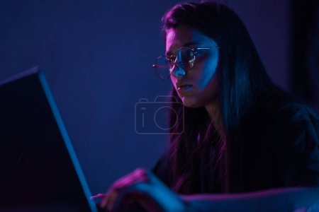 Foto de Attractive young woman working in home at night. Girl using laptop. - Imagen libre de derechos