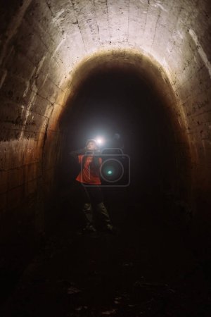 Photo for A young female digger with a flashlight explores the tunnel - Royalty Free Image
