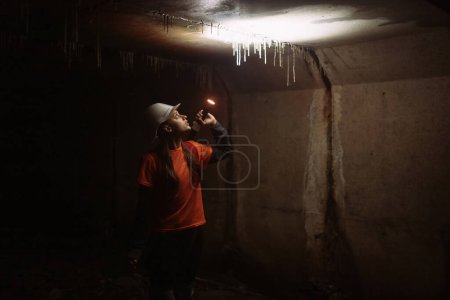 Téléchargez les photos : Une jeune femme creuseuse avec une lampe de poche explore le tunnel - en image libre de droit