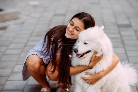 Foto de Una mujer joven abraza a un perro grande al atardecer en verano - Imagen libre de derechos