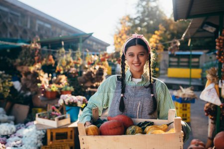 Photo for Farmer woman holds a wooden box with pumpkins in hands. Concept of market. - Royalty Free Image