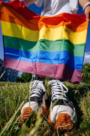 Téléchargez les photos : Une jeune femme tenant un drapeau de fierté LGBT entre ses mains. Fermer la vue, photo recadrée - en image libre de droit