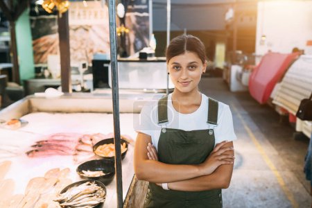 Téléchargez les photos : Poissonnerie souriante debout près du comptoir de la boutique de fruits de mer - en image libre de droit