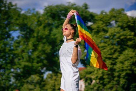 Téléchargez les photos : Jeune femme avec drapeau de fierté lgbt marche dans le parc. - en image libre de droit