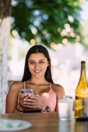 Téléchargez les photos : Photo de charmante jolie jeune femme communiquant gadget moderne souriant à l'extérieur de la rue urbaine de la ville - en image libre de droit