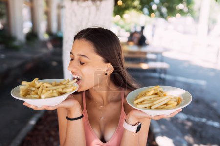 Téléchargez les photos : Women hold french fries on white plates. Street cafe - en image libre de droit