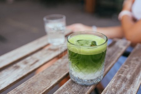 Foto de Iced green matcha latte tea in a glass on wooden table at modern style cafe. Tasty morning drinks. - Imagen libre de derechos