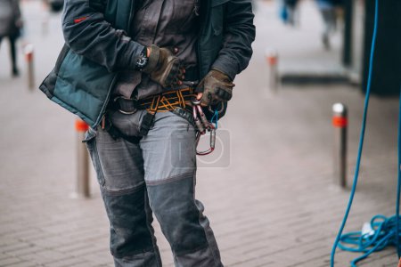 Foto de Worker climber preparing for work. Climber tightens the safety belt and check fixing and carbines - Imagen libre de derechos