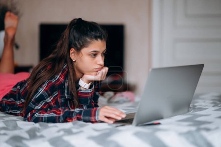 Photo for Selective focus of young woman work while with laptop lying on bed - Royalty Free Image