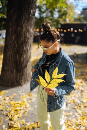 Téléchargez les photos : Une femme dans un parc d'automne tient une feuille jaune dans sa main - en image libre de droit