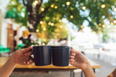 Téléchargez les photos : Image rapprochée d'un couple de personnes cliquetis tasses à café ensemble dans le café - en image libre de droit