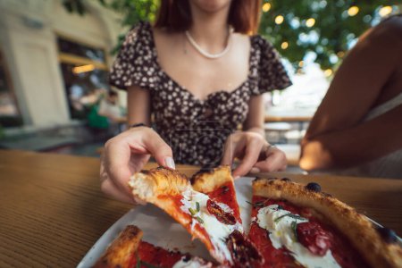 Photo for Charming beautiful woman takes a slice of pizza. An attractive girl is hungry and loves the taste. - Royalty Free Image