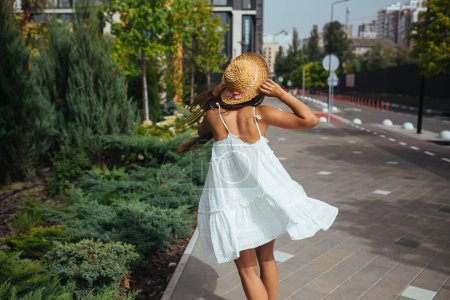 Photo for Young beautiful brunette woman in dress walking on the street, summer embankment outdoors - Royalty Free Image