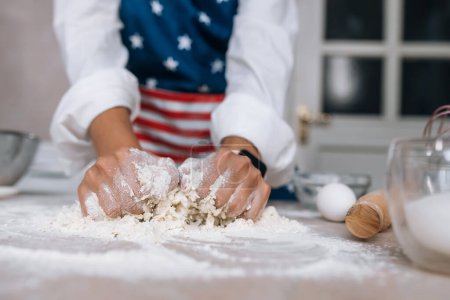 Photo for The process of making dough for a meal close-up. A young housewife in an apron kneads dough with her hands. - Royalty Free Image