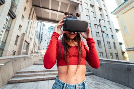 Téléchargez les photos : A woman in a virtual reality helmet walks down the street - en image libre de droit