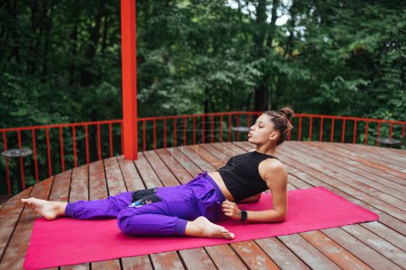 Photo for A young woman in doing yoga in the yard on the veranda - Royalty Free Image