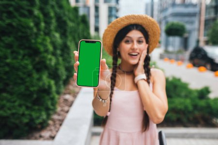 Téléchargez les photos : Young woman showing smartphone with green screen for replacement - en image libre de droit