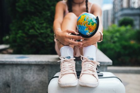 Téléchargez les photos : A beautiful young woman holds a small globe in her hands. Lifestyle and travel Concept - en image libre de droit