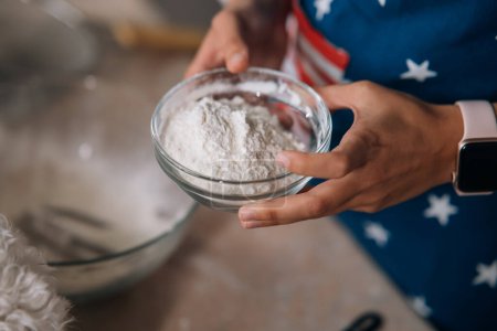 Foto de Primer plano de las manos femeninas sosteniendo la harina en un tazón en la cocina - Imagen libre de derechos