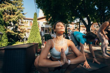 Foto de Una mujer hace yoga junto con su grupo al aire libre. concepto de estilo de vida saludable - Imagen libre de derechos