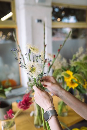 Foto de Florist woman makes a bouquet of fresh wildflowers. Close view - Imagen libre de derechos
