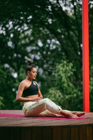Téléchargez les photos : Une jeune femme dans le yoga dans la cour sur la véranda - en image libre de droit