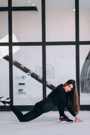 Foto de Vista lateral de chica flexible ejercitando postura de yoga en interiores. Concepto de yoga. - Imagen libre de derechos