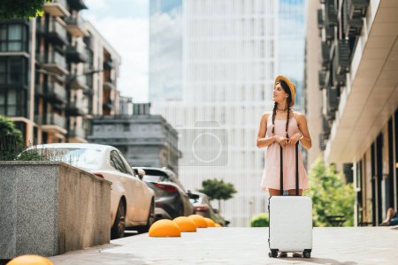 Foto de Joven mujer hermosa con una maleta en el fondo de una ciudad moderna - Imagen libre de derechos