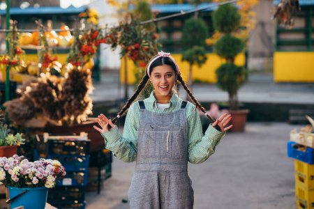 Téléchargez les photos : Femme agricultrice ludique en salopette de denim souriant sincèrement tout en posant. Le concept d'agriculture. - en image libre de droit